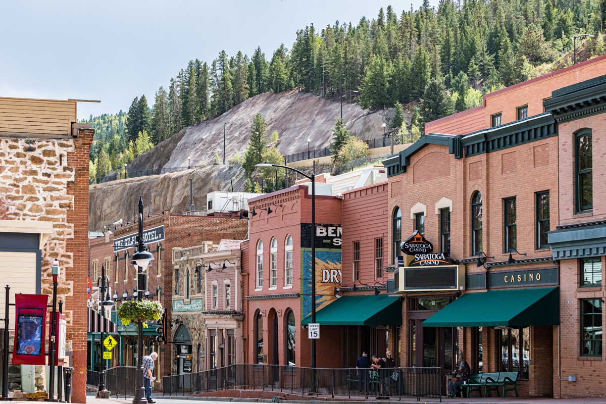 A row of red-brick, Victorian-era buildings line the main street; several have green awnings