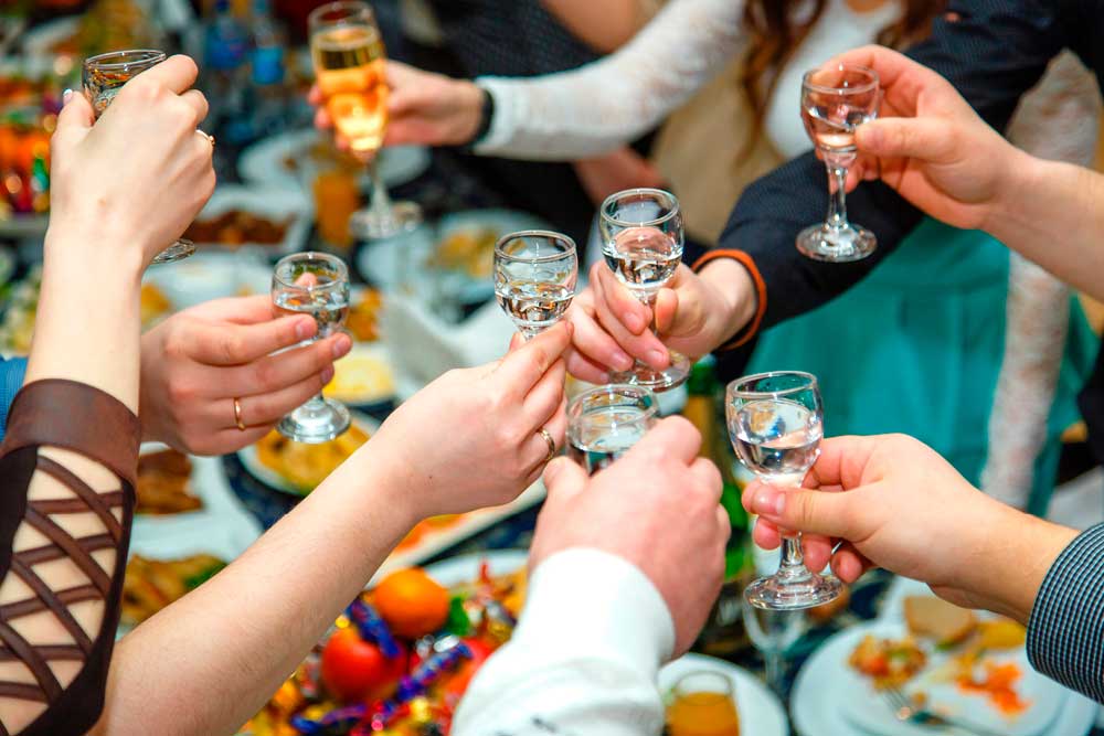 A bunch of arms holding small glasses of wine clink for a toast