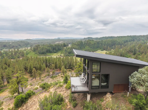 The side view of The Ridge cabin in Pagosa Springs, Colorado, with trees, shrubbery and a cloud-filled sky.