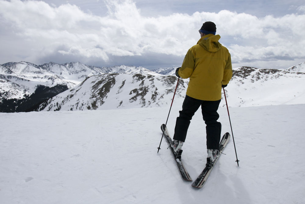 A person in a yellow jacket downhill skis at the the slopes in Copper Mountain Resort.