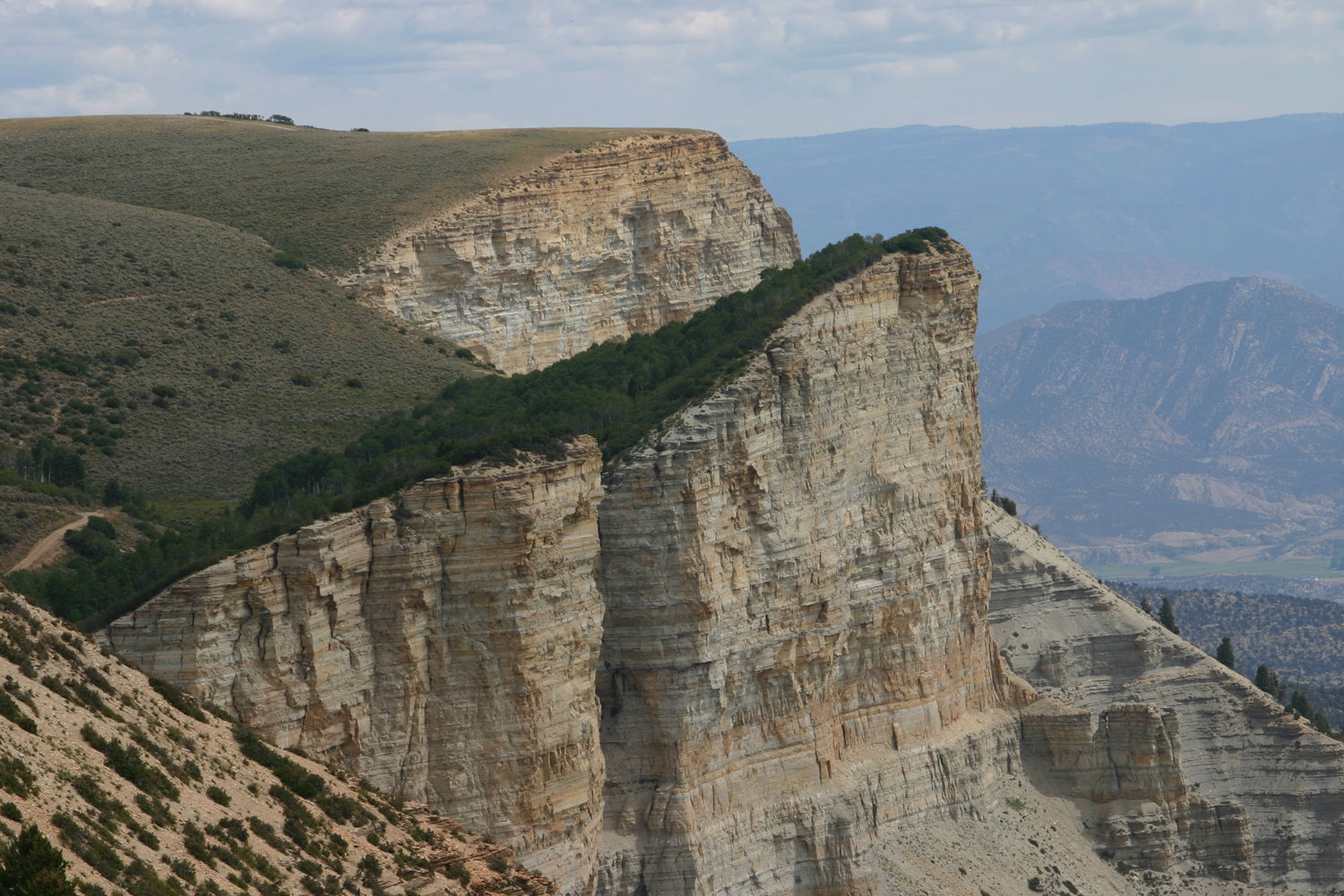 The anvil point above Rifle's sand-colored cliff face. The top of the point is covered in green grass.