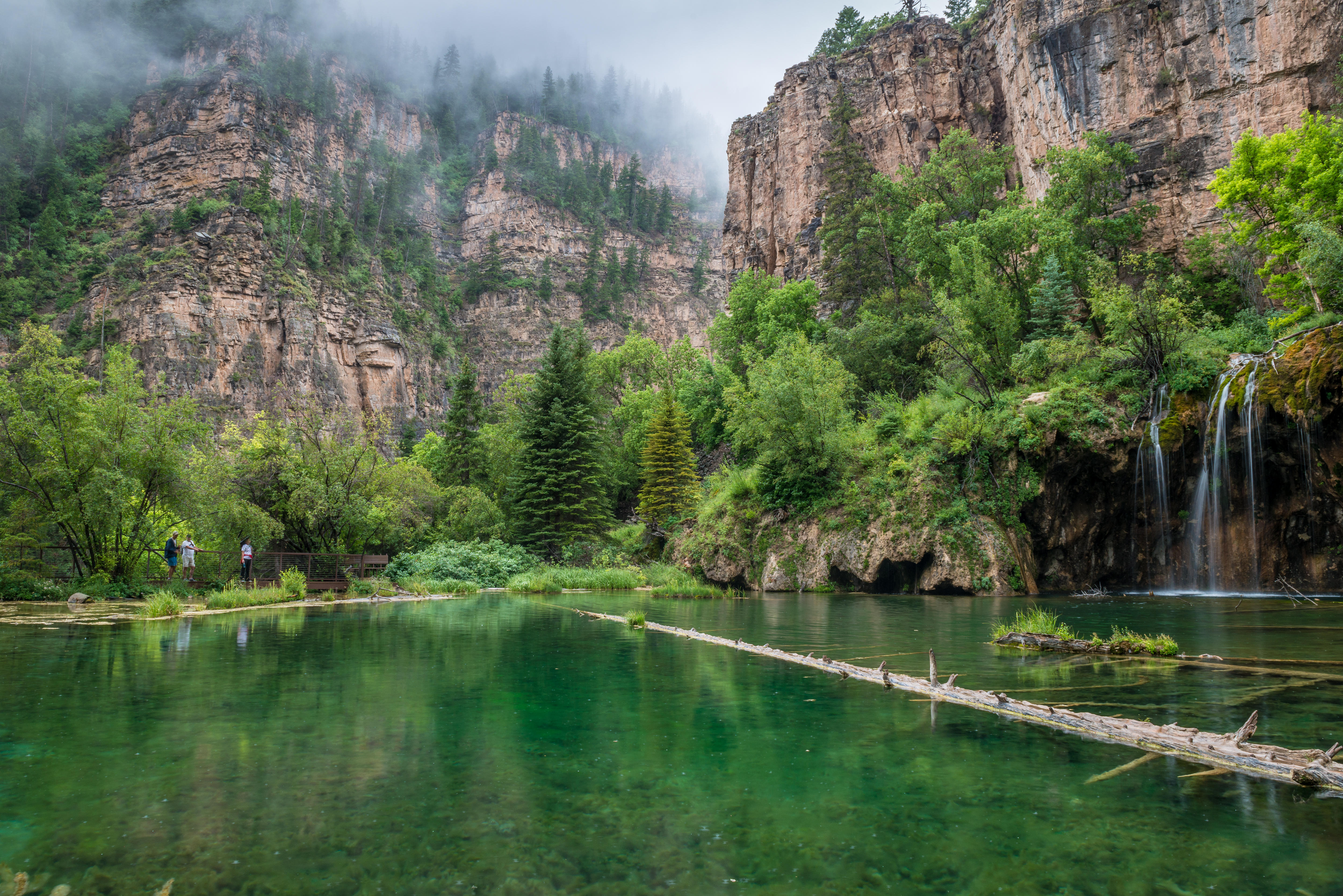 Hanging Lake reflecting the green trees and mountains on a foggy day near Glenwood Springs